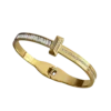 Bracelet jonc doré pour femme avec design inspiré du clou, orné de détails brillants sur la partie supérieure et doté d'une fermeture intégrée discrète.
