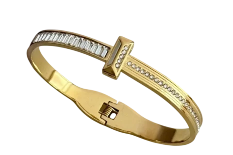Bracelet jonc doré pour femme avec design inspiré du clou, orné de détails brillants sur la partie supérieure et doté d'une fermeture intégrée discrète.