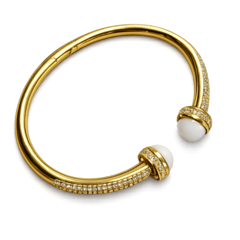 Bracelet jonc ouvert doré pour femme avec deux perles blanches décoratives aux extrémités et détails brillants incrustés sur le contour du bijou.