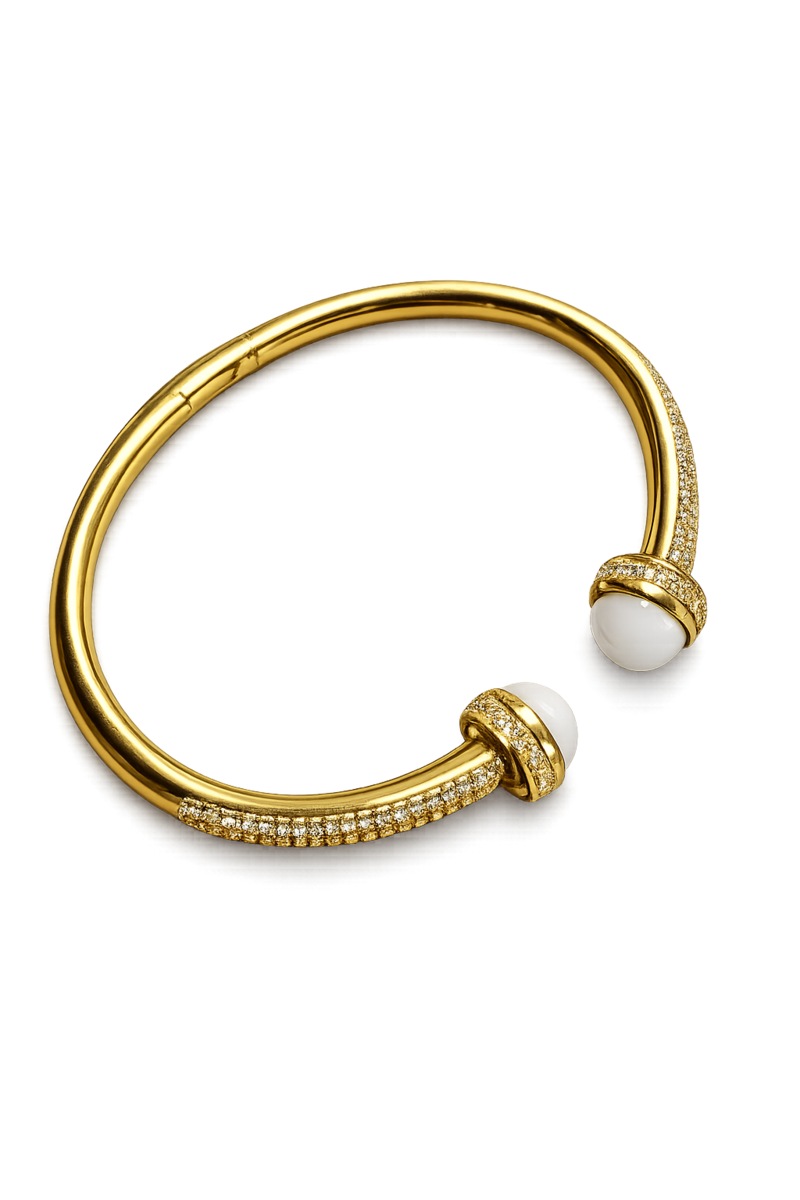 Bracelet jonc ouvert doré pour femme avec deux perles blanches décoratives aux extrémités et détails brillants incrustés sur le contour du bijou.