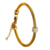 Bracelet jonc femme doré avec maille serpent et anneaux ornés de cristaux brillants, présenté dans un écrin de bijouterie haut de gamme.