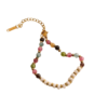 Bracelet femme haut de gamme en pierres naturelles pastel multicolores avec perles blanches et finitions dorées, présenté sur un tissu satiné beige.