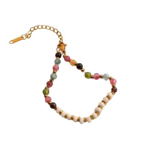Bracelet femme haut de gamme en pierres naturelles pastel multicolores avec perles blanches et finitions dorées, présenté sur un tissu satiné beige.