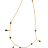 Collier doré pour femme avec chaîne fine ajustable, pampilles suspendues et éléments décoratifs verts, présenté sur un fond beige élégant.