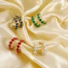 Boucles d’oreilles créoles pour femme avec pierres carrées colorées bleu, vert, rouge et transparent sur monture dorée élégante.