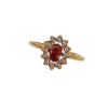Bague dorée pour femme avec pierre rouge ovale centrale entourée d'un halo de petites pierres scintillantes, au design élégant et raffiné.