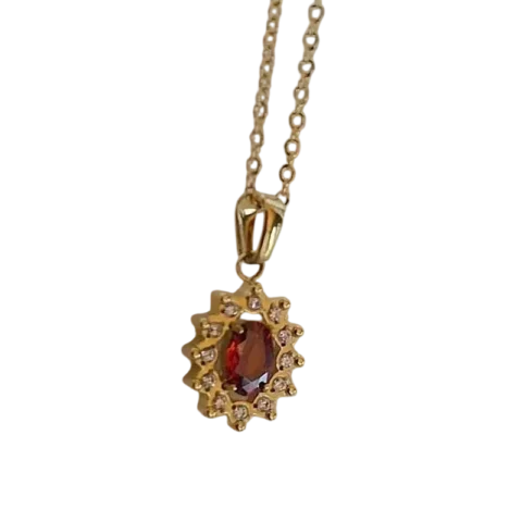 Collier doré pour femme avec pendentif composé d'une pierre rouge ovale entourée d'un halo de petites pierres scintillantes, au style élégant et raffiné.