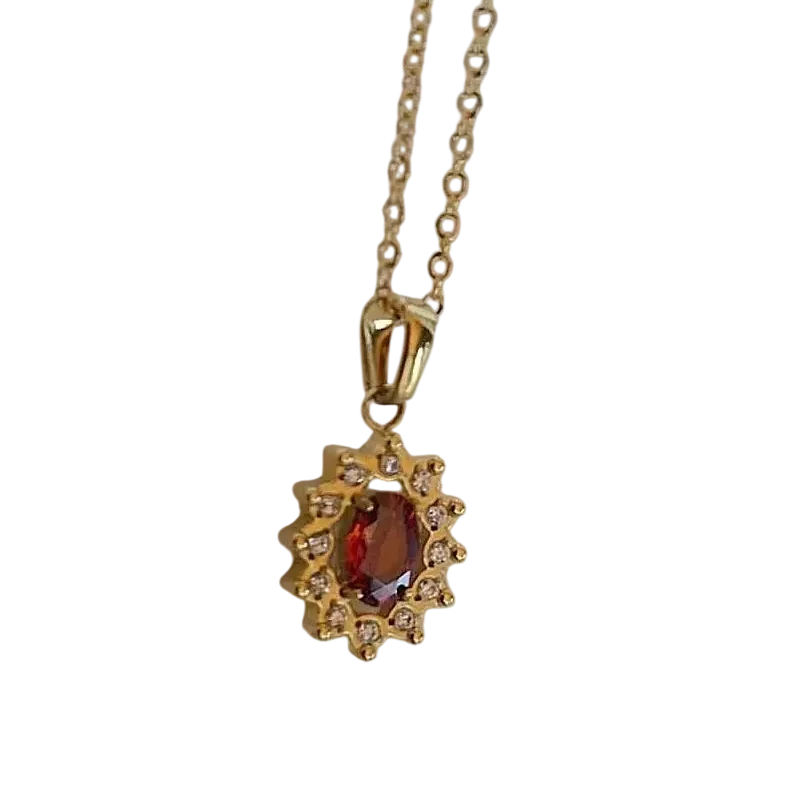 Collier doré pour femme avec pendentif composé d'une pierre rouge ovale entourée d'un halo de petites pierres scintillantes, au style élégant et raffiné.