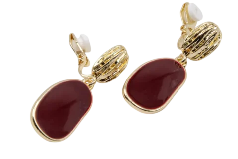 Boucles d'oreilles à clip pour femme en métal finition dorée avec élément décoratif texturé et pendentif bordeaux de forme organique.