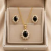 Ensemble de bijoux femme doré comprenant un collier et des boucles d'oreilles avec pierre noire ovale entourée de pierres transparentes au style élégant.