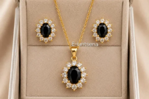 Ensemble de bijoux femme doré comprenant un collier et des boucles d'oreilles avec pierre noire ovale entourée de pierres transparentes au style élégant.
